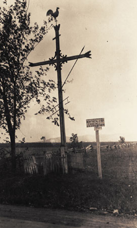 Wayside cross adorned with a rooster, a spear and a ladder. Sainte-Madeleine, Qubec, 1923., © CMC/MCC, Edouard Zotique Massicotte, 60067