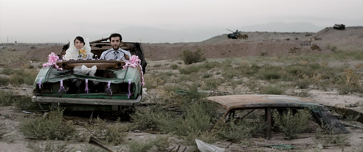 A couple is riding in an old truck through the desert.