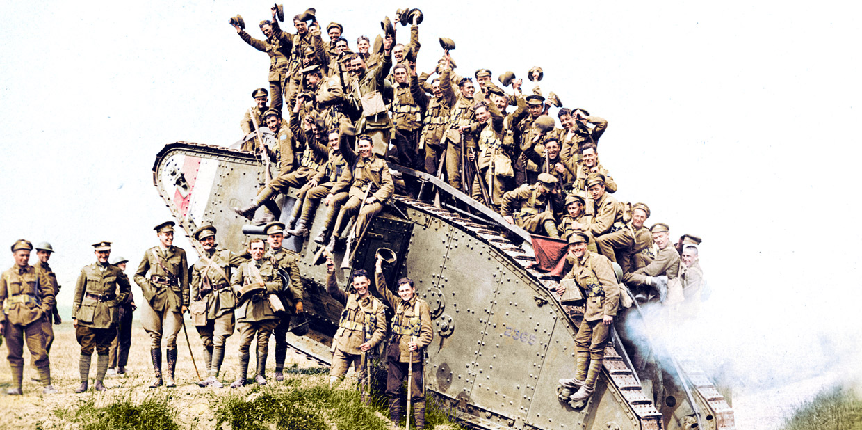 A group of soldiers posing on top of a tank.