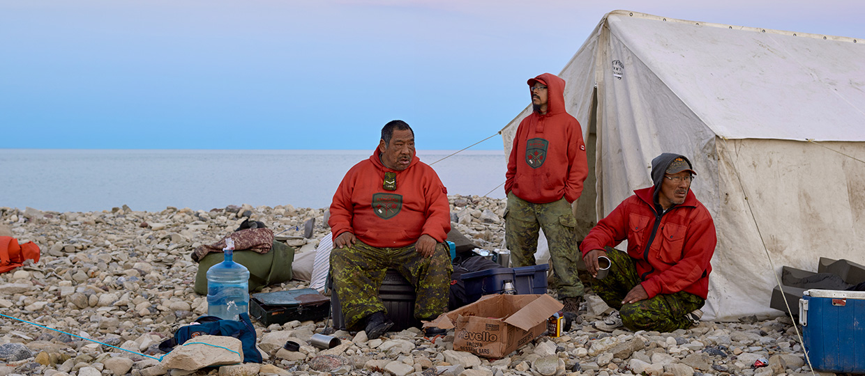 A group of people sitting in front of a tent up North.