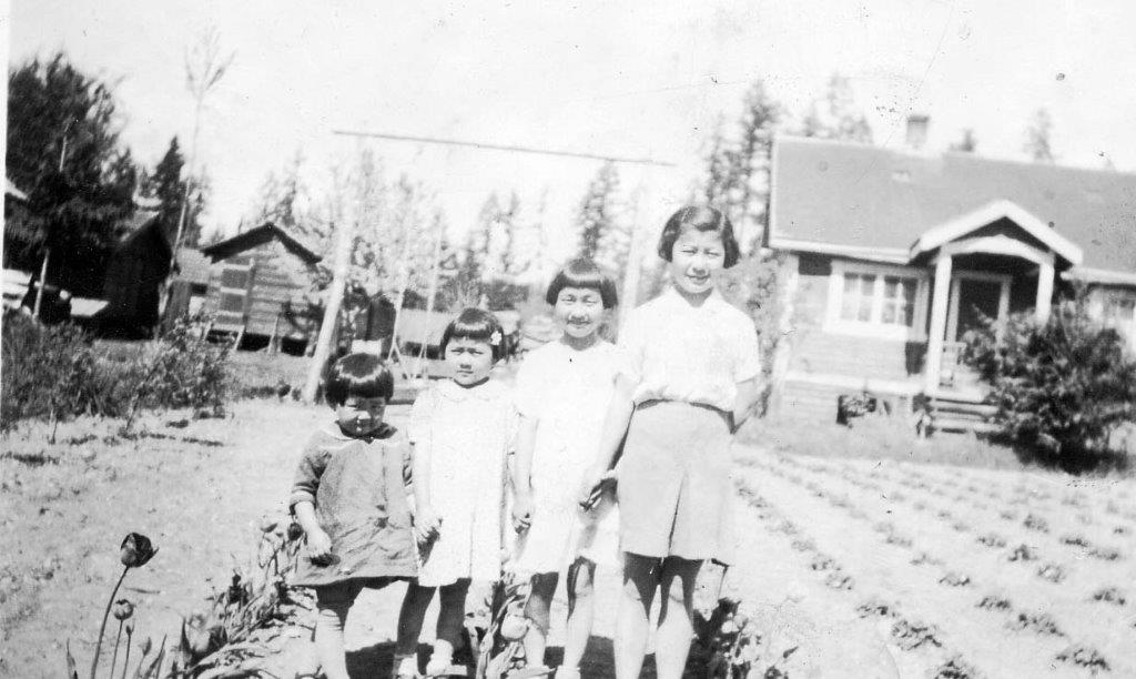 Four young sisters standing in front of their home