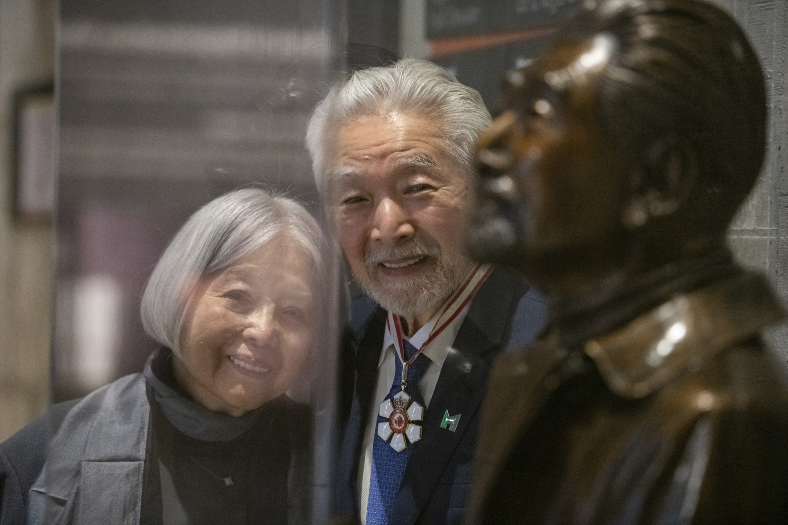 A man and woman standing next to a bronze statue in Ottawa.