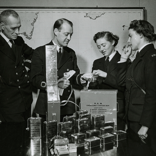 A group of people standing around a table with boxes in front of them at the Canadian War Museum in Ottawa.