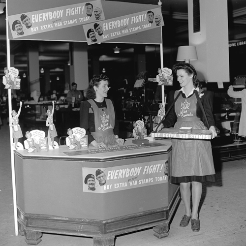 Two women standing in front of a food stand.