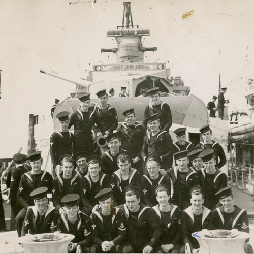 A group of men posing in front of a ship at the Canadian War Museum in Ottawa.