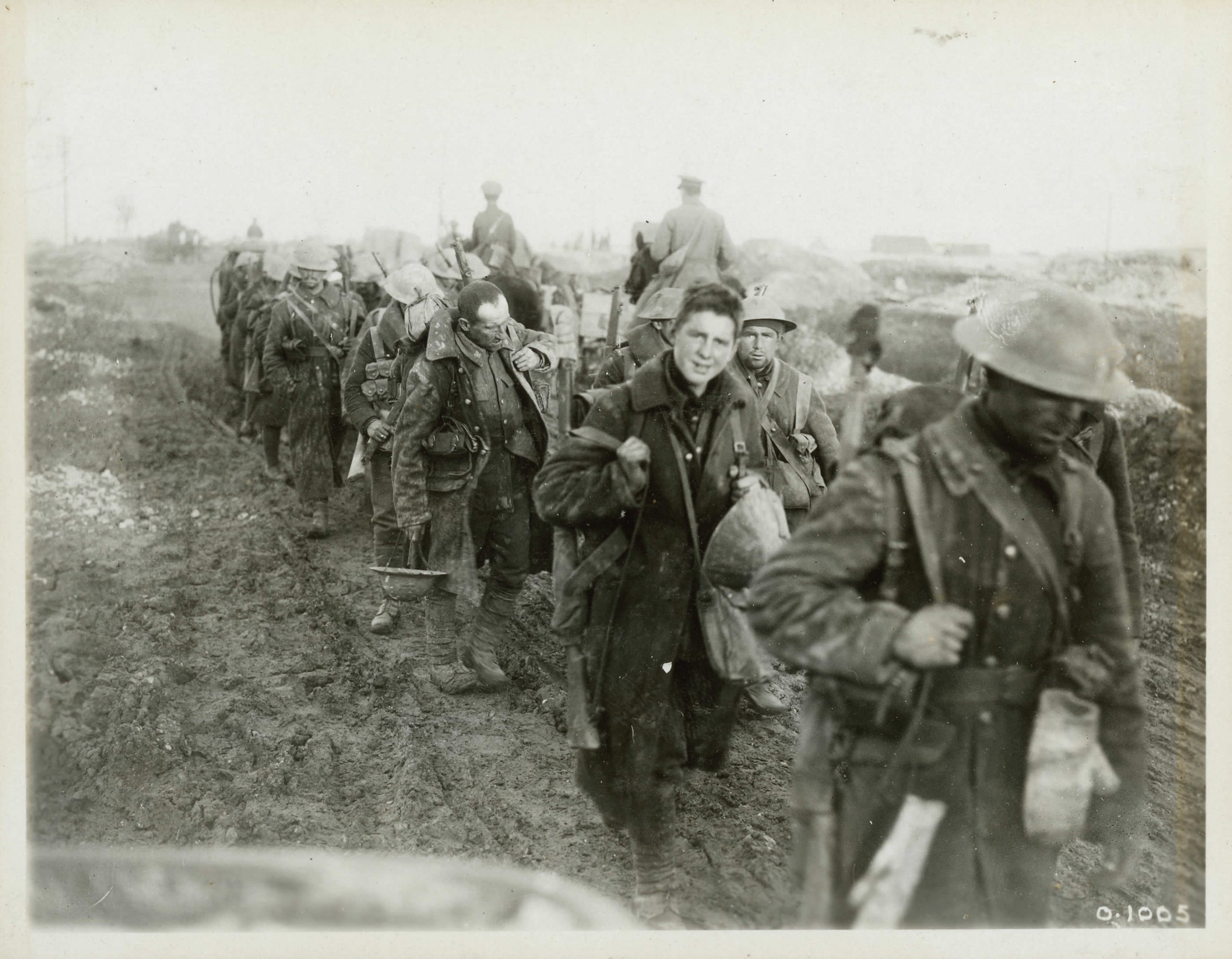 A group of soldiers walking down a dirt road.