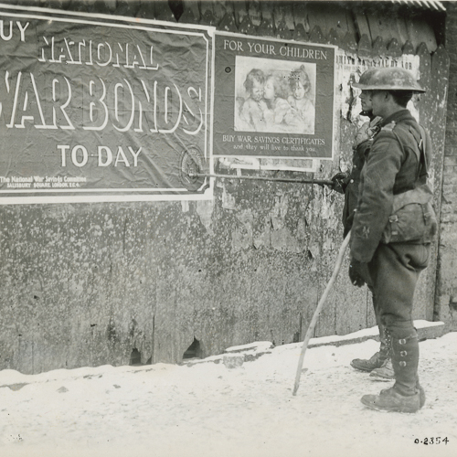 A soldier standing in front of a wall with a sign that says buy war bonds today.