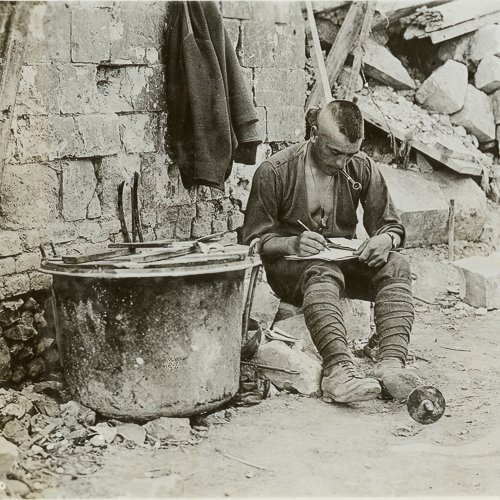 A man sitting and writing near a pile of rubble