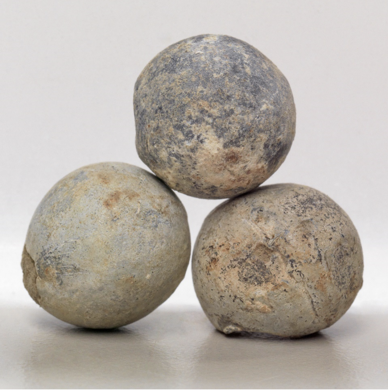 Three shrapnel bullets on a white surface.