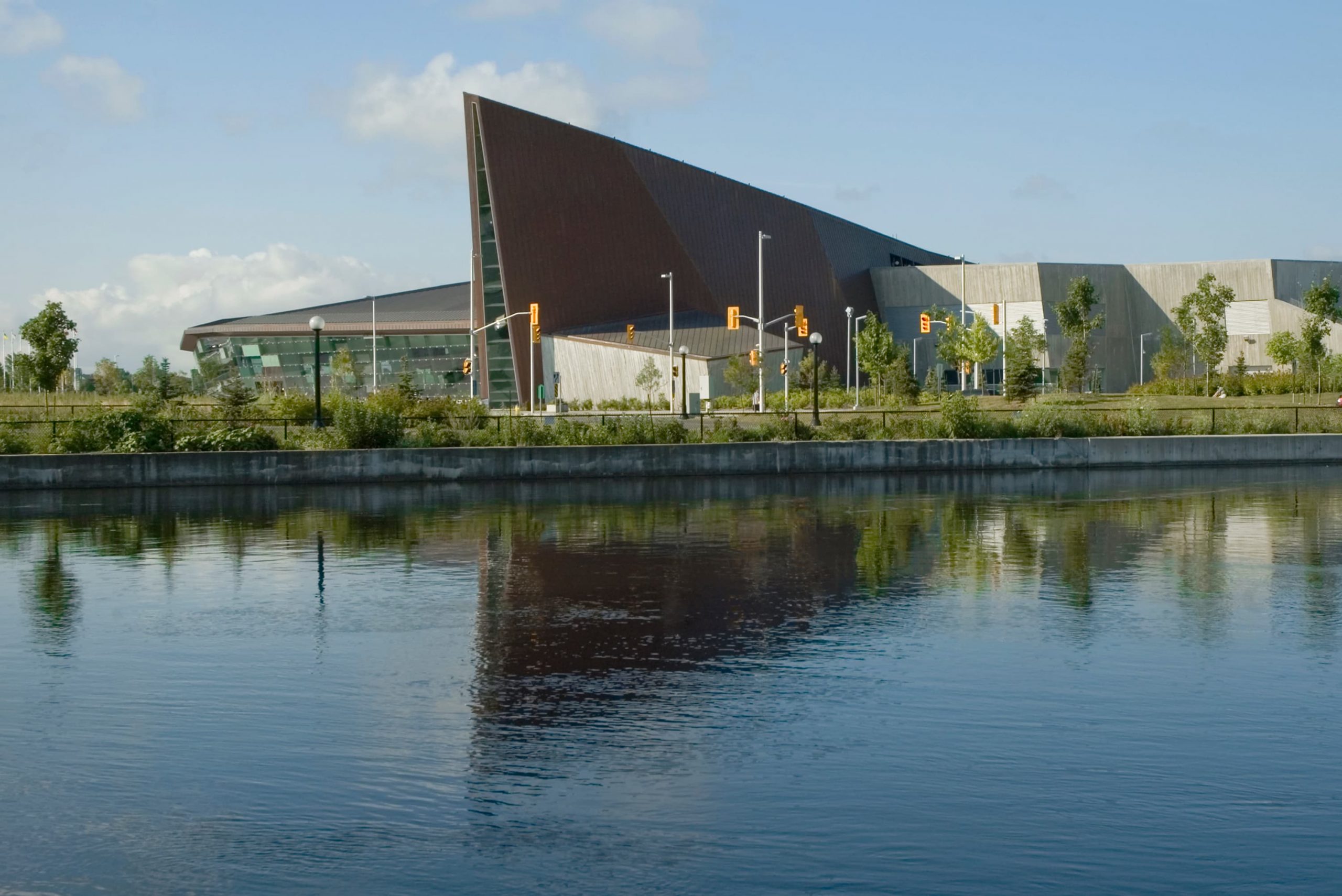 The Canadian War Museum, located in Ottawa, is a striking building situated next to a tranquil body of water.