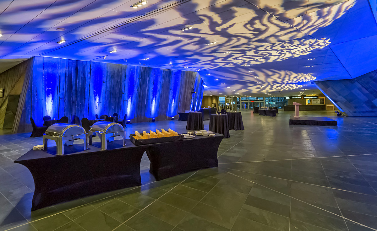 The Lobby with tables and chairs at the Canadian War Museum, complemented by striking blue lighting.