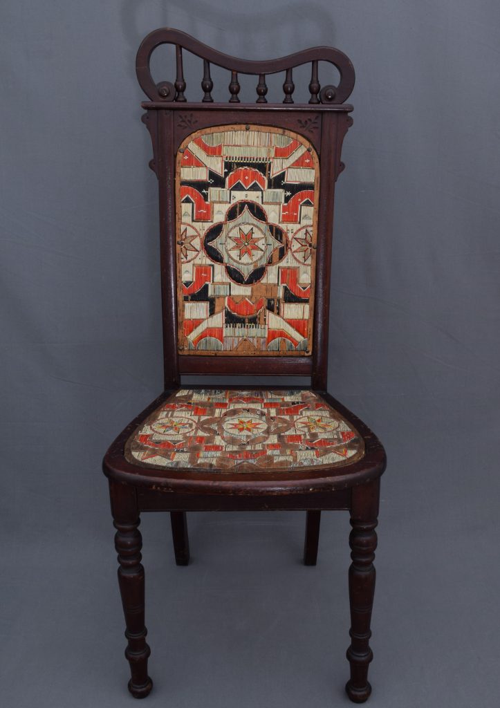 A wooden chair with an ornate upholstered seat.