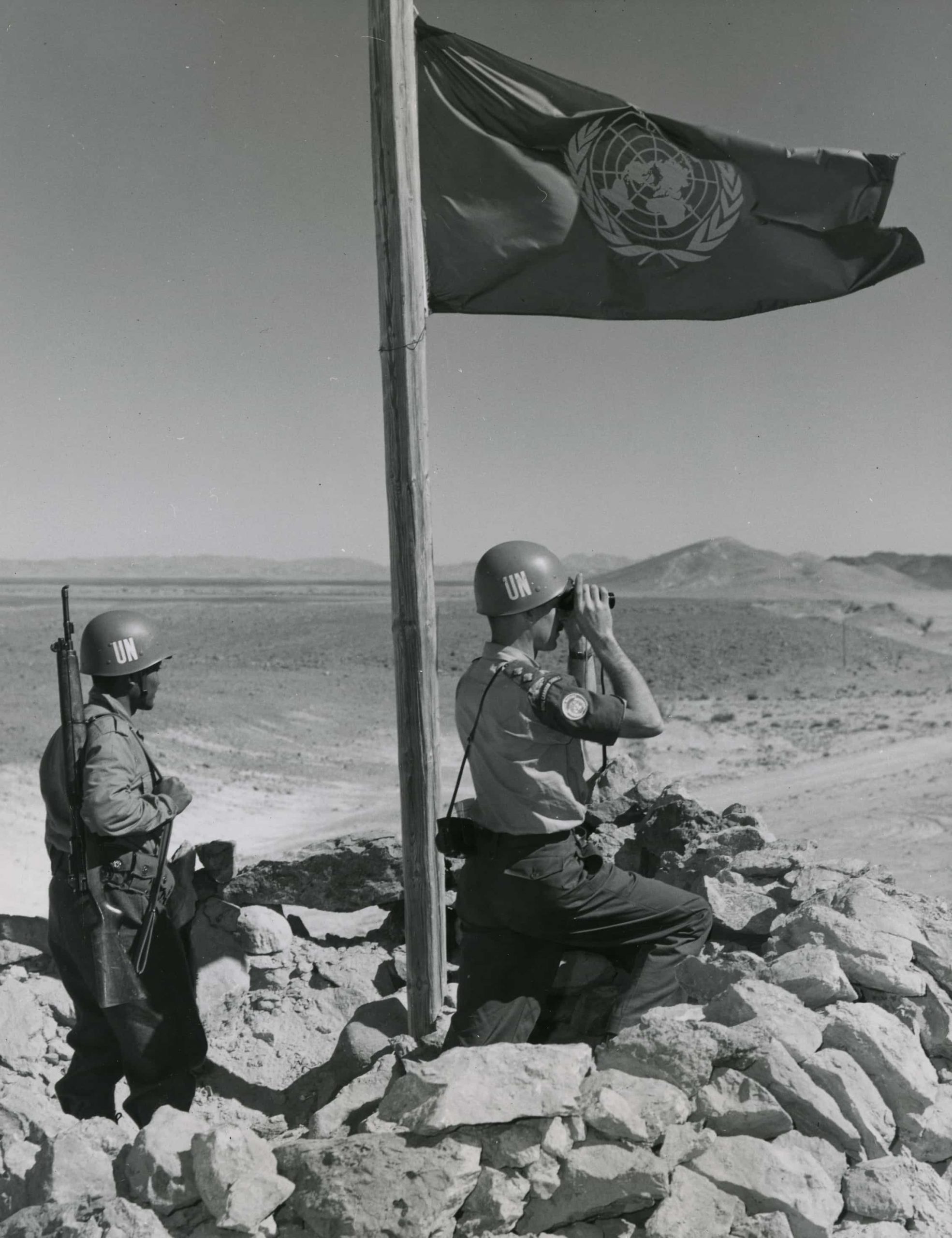 Two soldiers at the Canadian War Museum in Ottawa look at a flag on top of a hill.