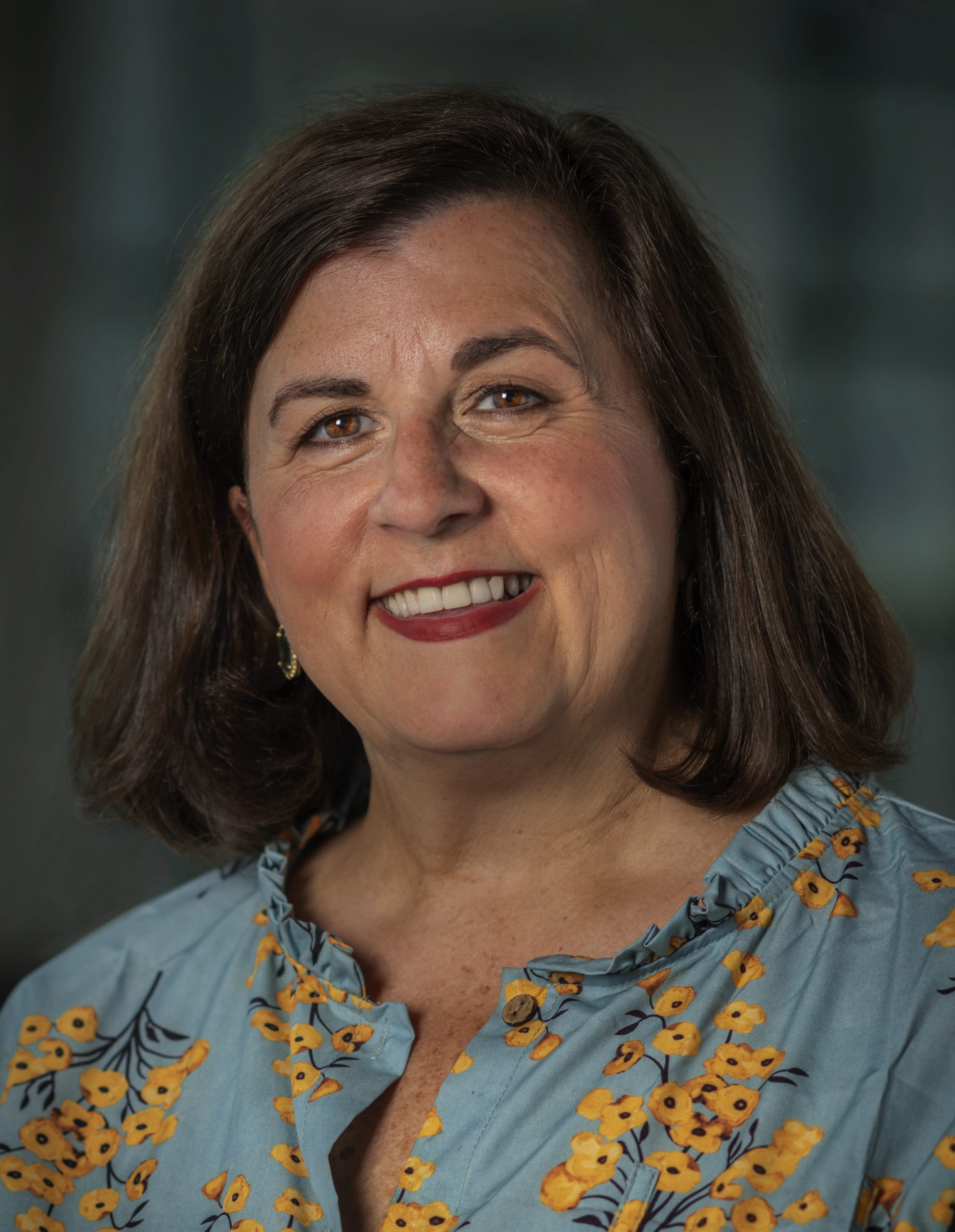 A smiling woman in a floral top.