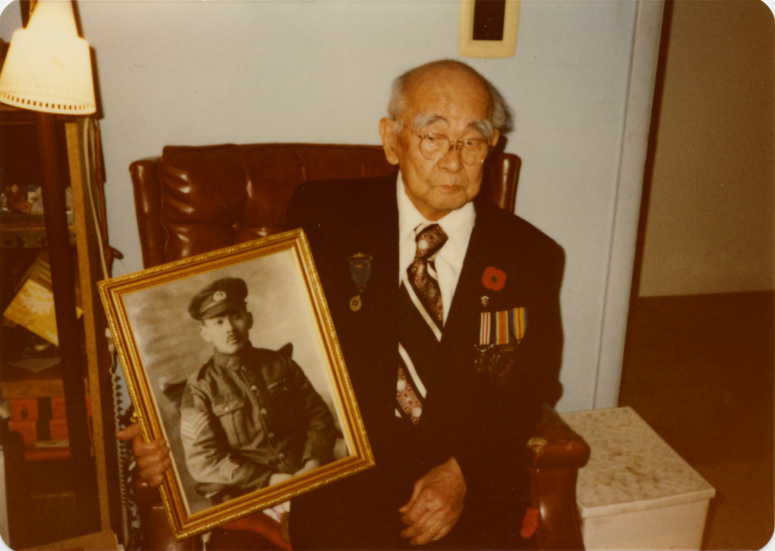 An older man in Ottawa holding a picture of a military man at the Canadian War Museum.