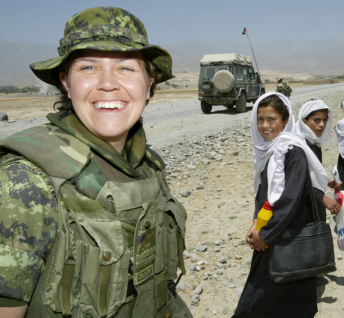 A female soldier in the Middle East smiles at camera